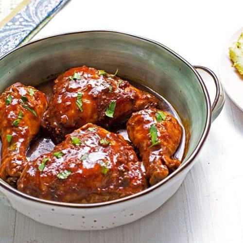 בשר בתבשיל עם רוטב מונח בכלי חרס, מגיש לצד ירקות מבושלים.